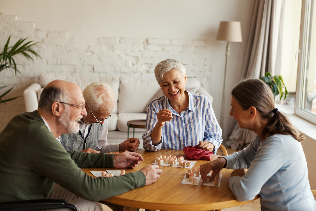 Four residents laughing together around a bingo table